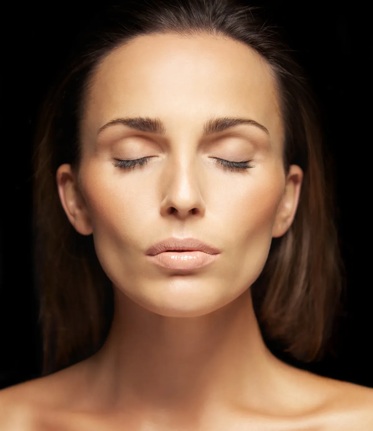 Pretty young brunette woman with her eyes closed isolated on black background. Pretty young female dreaming on black background